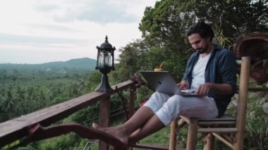 Sakallı, genç, yakışıklı bir adam inanılmaz bir gün batımına bakan bir kafede dizüstü bilgisayarla çalışıyor. Seyahat tutkusu olan serbest çalışan, kafede oturmuş meyve kokteyli yudumlayan..