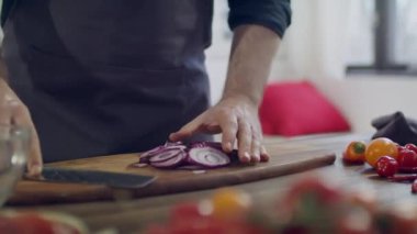 Şef ev mutfağında sebze doğruyor. Sağlıklı yiyecekler için sebze doğramak. Aşçının masasında taze sebzeler. Genç bir adam mutfakta yemek hazırlıyor..