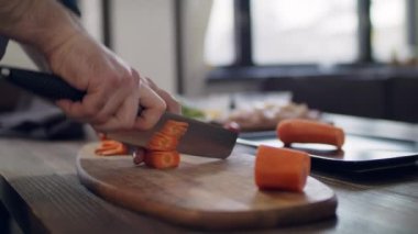 Şef ev mutfağında sebze doğruyor. Sağlıklı yiyecekler için sebze doğramak. Aşçının masasında taze sebzeler. Genç bir adam mutfakta yemek hazırlıyor..