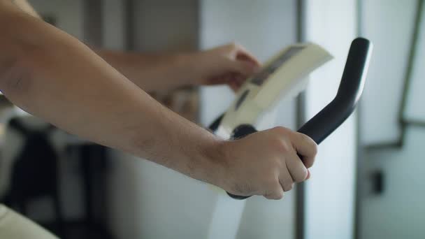 Een jonge knappe man traint op een stationaire fiets — Stockvideo