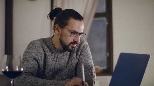 चश्मे में एक युवा, सुंदर आदमी लैपटॉप पर काम करता है . — स्टॉक वीडियो