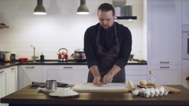 Bir adam evin içindeki mutfakta hamur hazırlar..