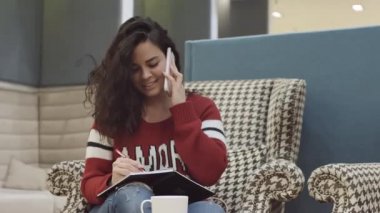 Genç ve güzel bir kız rahat bir ofiste çalışıyor. Kadın telefonda konuşuyor.. 