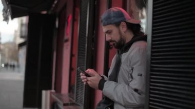 Güneşli bir sonbahar gününde, şehir sokağında telefonu olan genç yakışıklı bir adam..