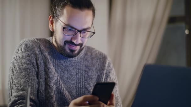 Un homme avec des lunettes devant un écran d'ordinateur le soir. — Video