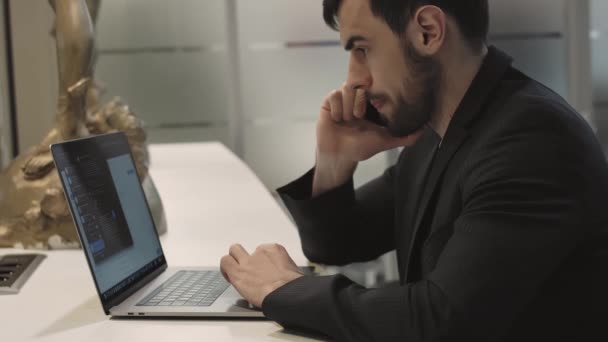 Ung fokuseret smuk mandlig forretningsmand arbejder på en bærbar computer. – Stock-video