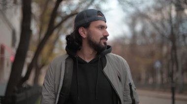 Genç ve çekici bir adam güneşli bir sonbahar gününde şehir parkında kameraya bakar.. 