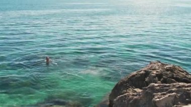 Turistler açık Karadeniz 'de güneşli bir yaz gününde kayaların arasında yüzerler..