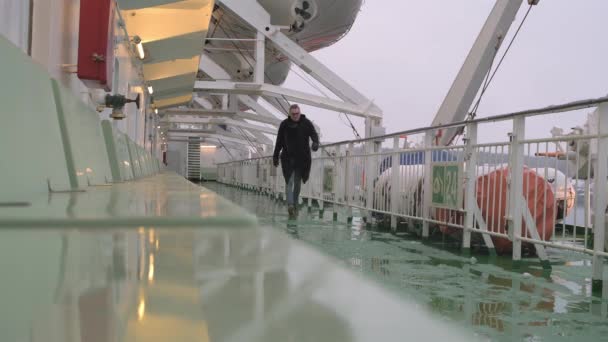 En ung man i rock går längs det tomma däcket på fartyget.. — Stockvideo