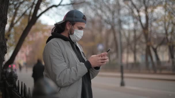 Молодий красивий чоловік розмовляє по телефону на вулиці маленького міста — стокове відео