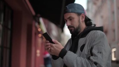 Güneşli bir sonbahar gününde, şehir sokağında telefonu olan genç yakışıklı bir adam..