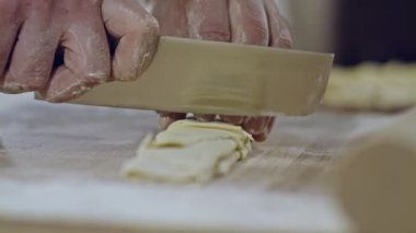 Şef spagettiyi dilimliyor. Makarna hamuruna yakın çekim.