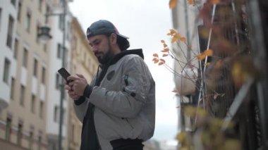 Güneşli bir sonbahar gününde, şehir sokağında telefonu olan genç yakışıklı bir adam..