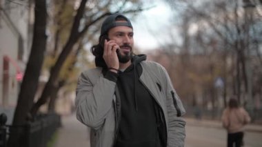 Young, handsome man talking on the phone on the street on a sunny spring day.