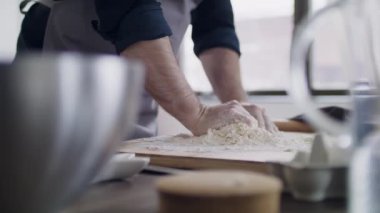 Close-up - hand of the cook. Flour is scattered on the table. Dough preparation.