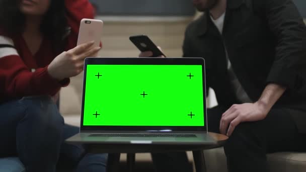 Chroma Key на экране ноутбука. Два человека сидят за ноутбуком. — стоковое видео