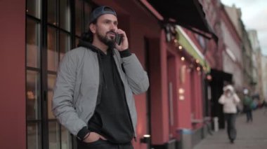 Genç, modern yakışıklı adam güneşli bahar gününün telefonundan konuşuyor..