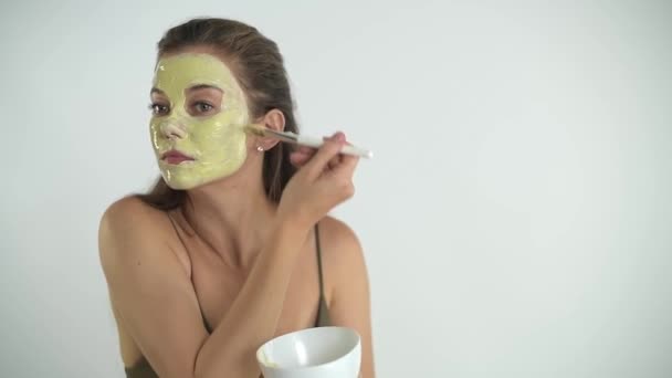 Une jeune belle fille applique un masque hydratant sur son visage — Video