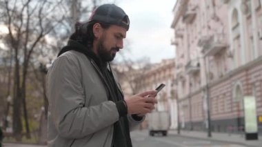 Güneşli bir sonbahar gününde, şehir sokağında telefonu olan genç yakışıklı bir adam..