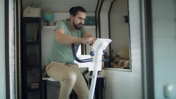年轻男子在家里骑自行车锻炼身体 — 图库视频影像