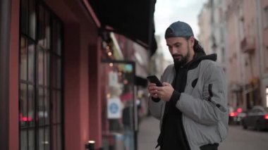 Güneşli bir sonbahar gününde, şehir sokağında telefonu olan genç yakışıklı bir adam..