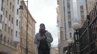 Güneşli bir sonbahar gününde, şehir sokağında telefonu olan genç yakışıklı bir adam..