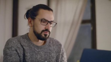 Gözlüklü genç ve yakışıklı bir adam dizüstü bilgisayarla çalışıyor..