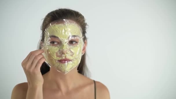 The girl removes the mask from her face with a sponge. Cosmetological procedure. — Stock Video