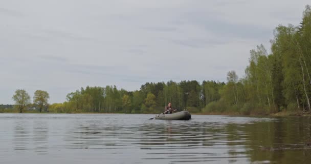 Rybářka plave po řece nebo jezeře na nafukovací lodi s vesly — Stock video