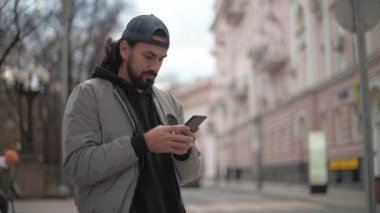 Güneşli bir sonbahar gününde, şehir sokağında telefonu olan genç yakışıklı bir adam..