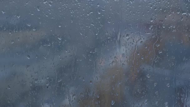 Gotas de lluvia en la ventana con una calle con coches borrosos detrás — Vídeos de Stock