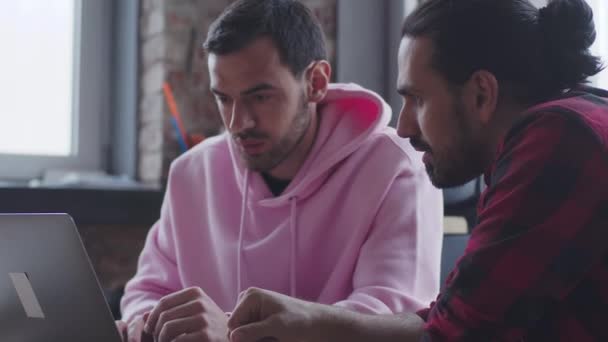 Un joven empresario con un portátil habla con un colega, en la oficina — Vídeo de stock