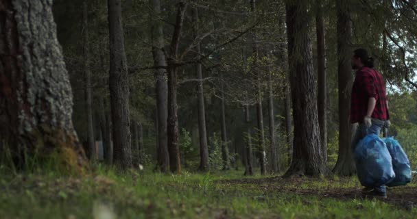 Ein Mann trägt Müllsäcke auf dem Weg. Müllabfuhr in der Natur — Stockvideo