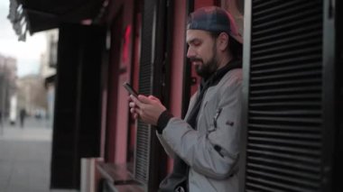 Güneşli bir sonbahar gününde, şehir sokağında telefonu olan genç yakışıklı bir adam..