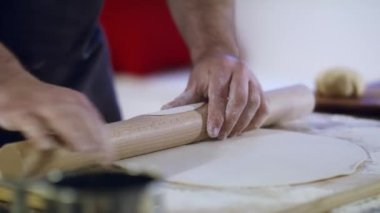 Bir aşçının ve hamurun yakın çekimi. Malzemeler masanın üstünde..