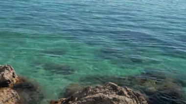 Açık mavi suyu olan deniz, mercan ve kayalık dibi gösterir..