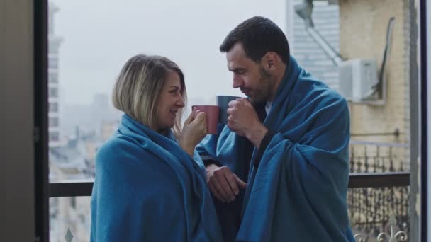 Man and women stand on the balcony with plaid and with mugs. — Stock Video