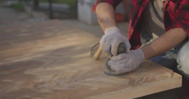 Solunum cihazlı, gözlüklü, parke tahtasını zımpara makinesiyle cilalayan bir adam..