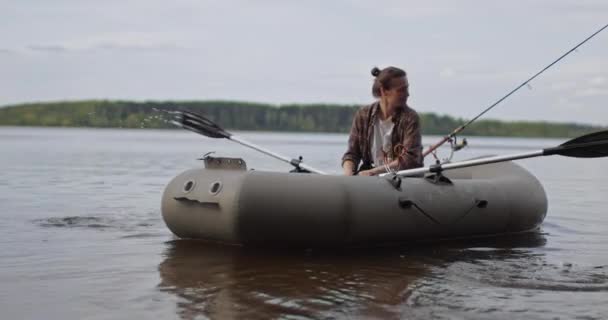 Belo filme cinematográfico. Menina pescador remo remos no lago um barco inflável. — Vídeo de Stock