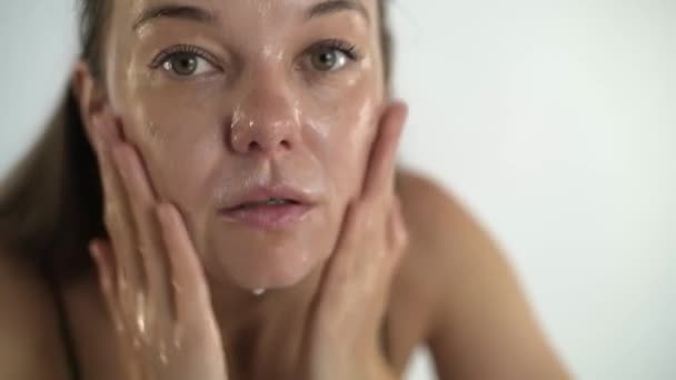 Una giovane bella ragazza si lava la faccia. Cura della pelle facciale. — Video Stock