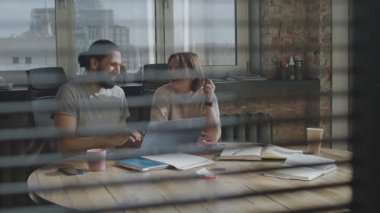 Arkadaşlar ortak bir projede birlikte çalışıyorlar, gülümsüyorlar ve gülüyorlar..