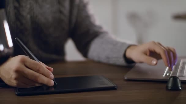 Κοντινό πλάνο ενός καλλιτέχνη χέρι σε ένα tablet γραφικών. Ο καλλιτέχνης αντλεί από ένα φορητό υπολογιστή. — Αρχείο Βίντεο