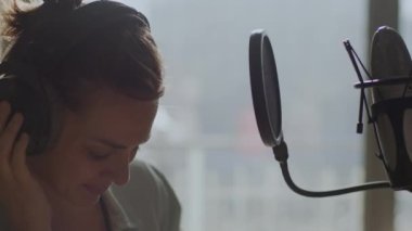 Genç bir kız duygusal olarak arka plandaki mikrofona şarkı söylüyor.