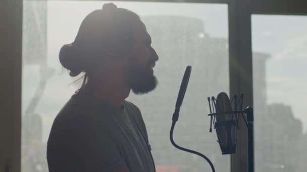 Fechar-se do homem barbudo atraente que canta em um microfone na luz solar — Vídeo de Stock