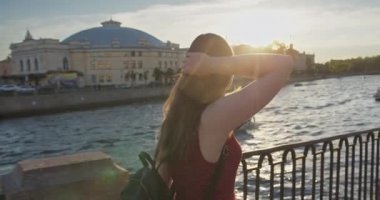 Sundress giymiş genç bir kız nehir kıyısında yürür.