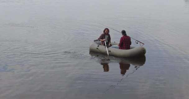 I giovani pescatori su una barca gonfiabile sul lago stanno pescando. Colpo cinematografico. — Video Stock