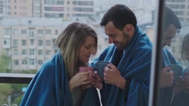 Erkekler ve kadınlar ekose ve kupalarla balkonda dururlar..