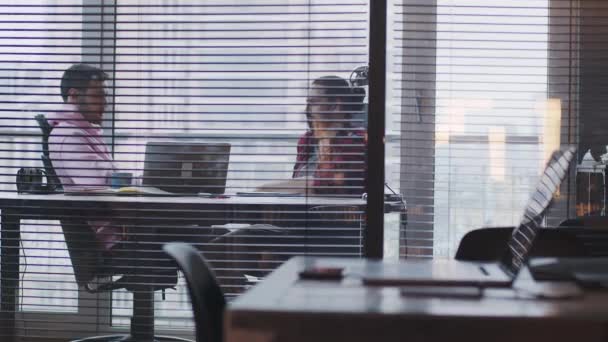 Un joven empresario con un portátil habla con un colega, en la oficina — Vídeo de stock