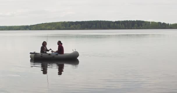 Young fishermen on an inflatable boat on the lake are fishing. Cinematic shot. — Stock Video
