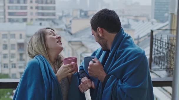 Man en vrouw staan op het balkon met ruitjes en mokken. — Stockvideo